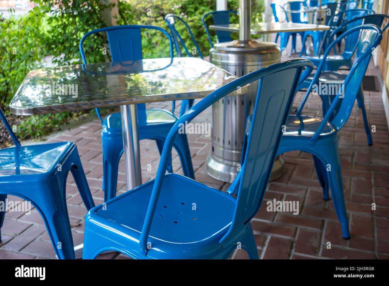 Colorful view of bright blue chairs gathered around a blue table on an outdoor patio at a restaurant Stock Photo