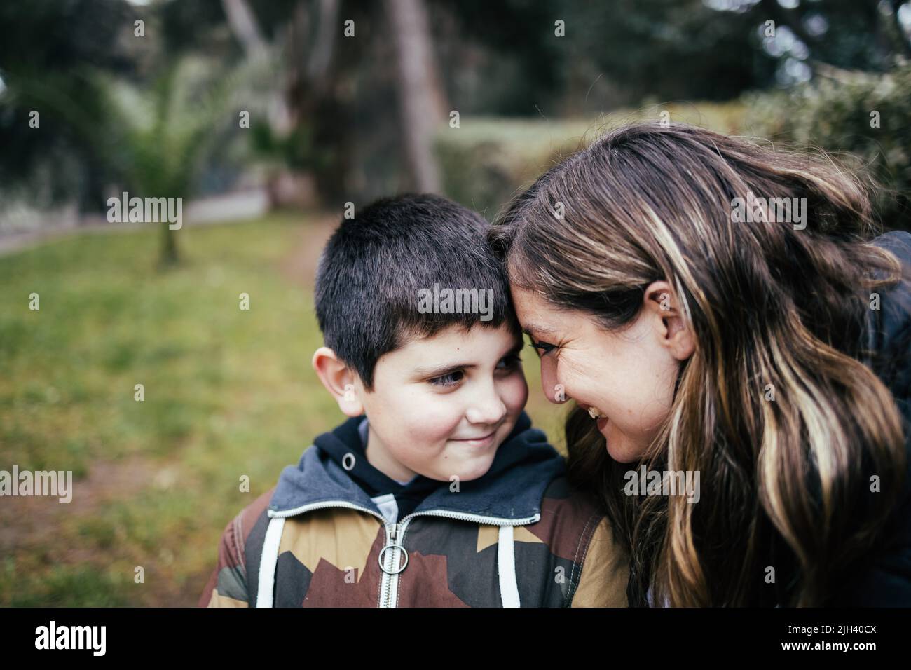 Young blonde latin mother hugging and laughing with her young son in the park. Single parent family Stock Photo