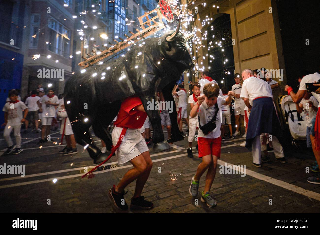 A child runs under the fueto bull in front of the fire bull during the ...