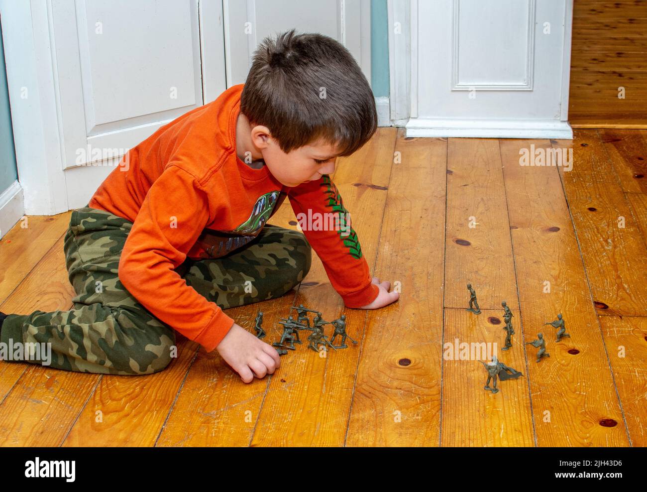 young boy plays with toy soldiers on the floor Stock Photo