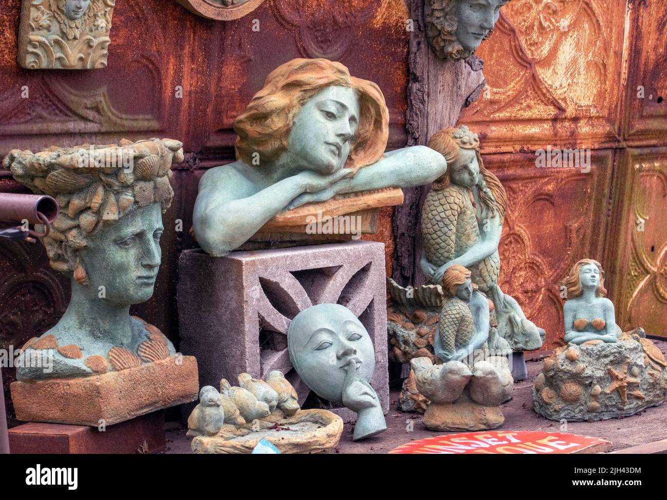 A variety of cement cast statues are offered for sale at an outdoor