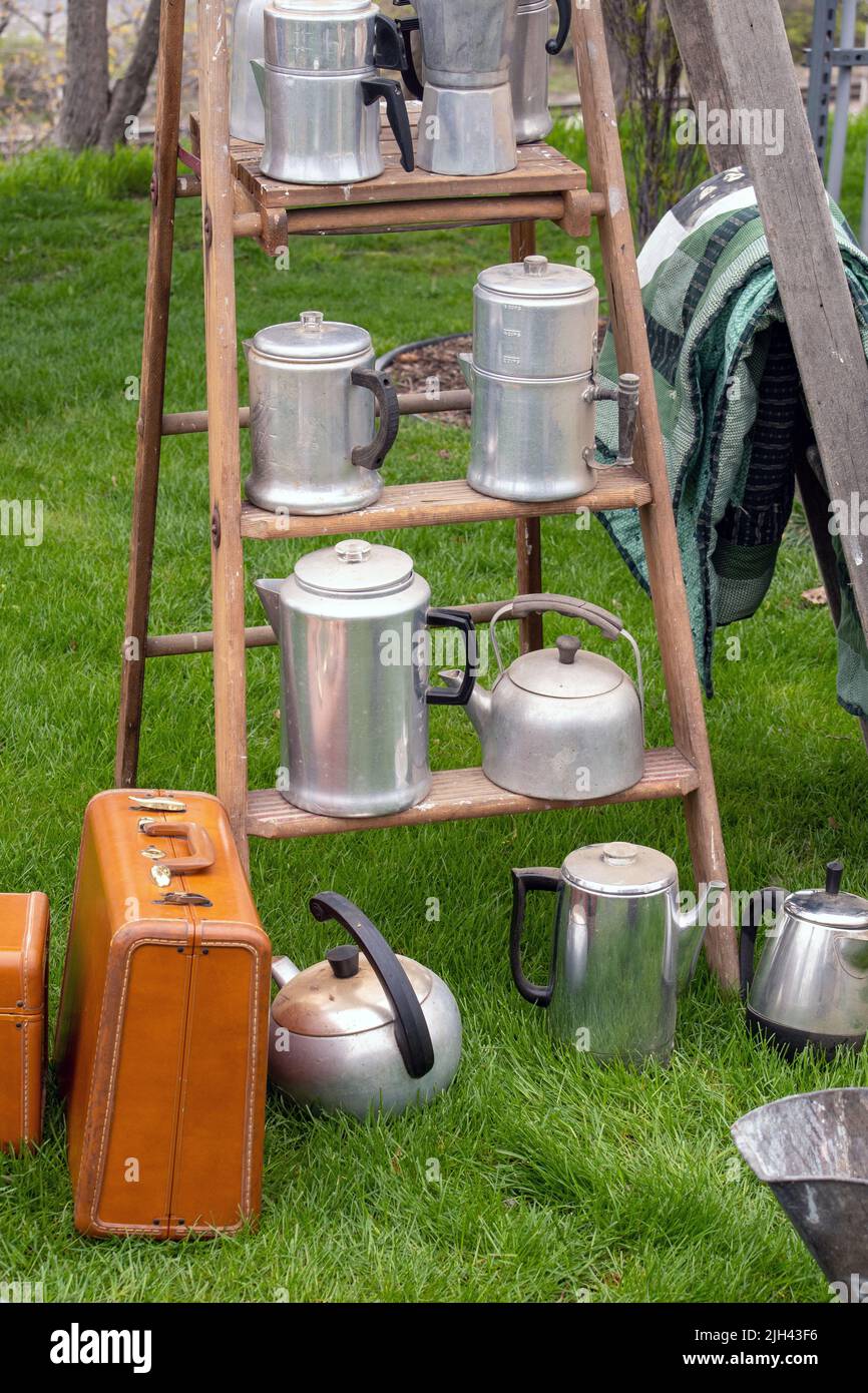 Coffee pots and tea kettles are placed on ladder steps as a display at an outdoor sale Stock Photo