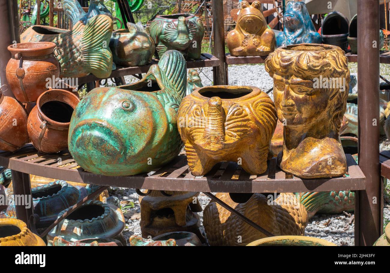 shelves of decorative ceramic planters sit outdoors at a fun garden center Stock Photo