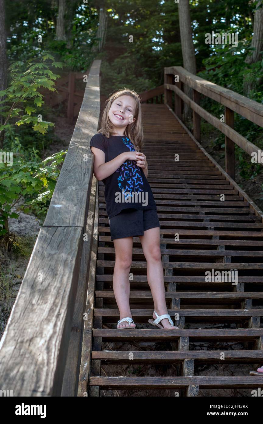 smiling girl poses on a very long staircase going dow to the beach in Michigan USA Stock Photo