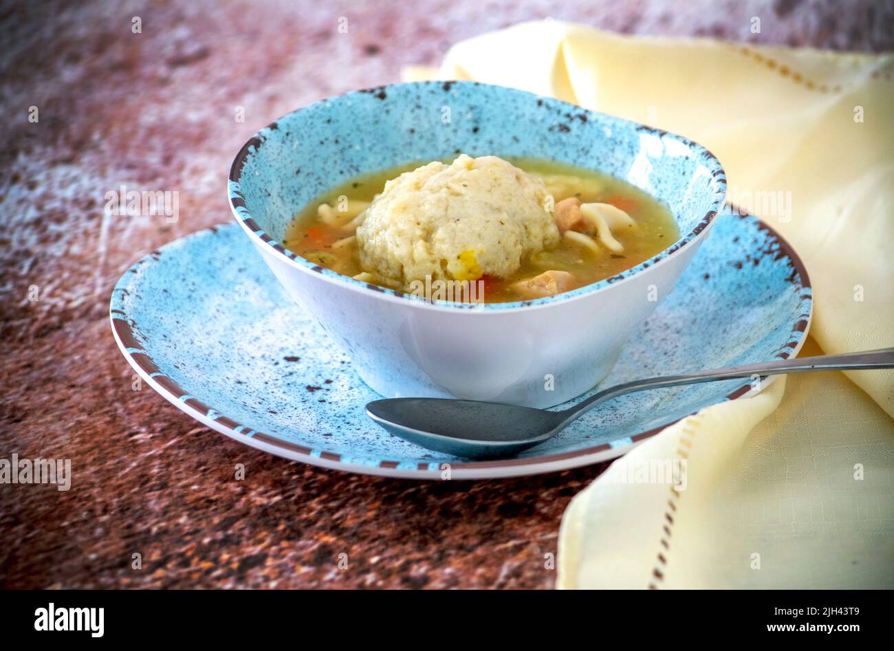 Warm bowl of chicken noodle soup, with a big, fluffy matzo ball floating on top Stock Photo