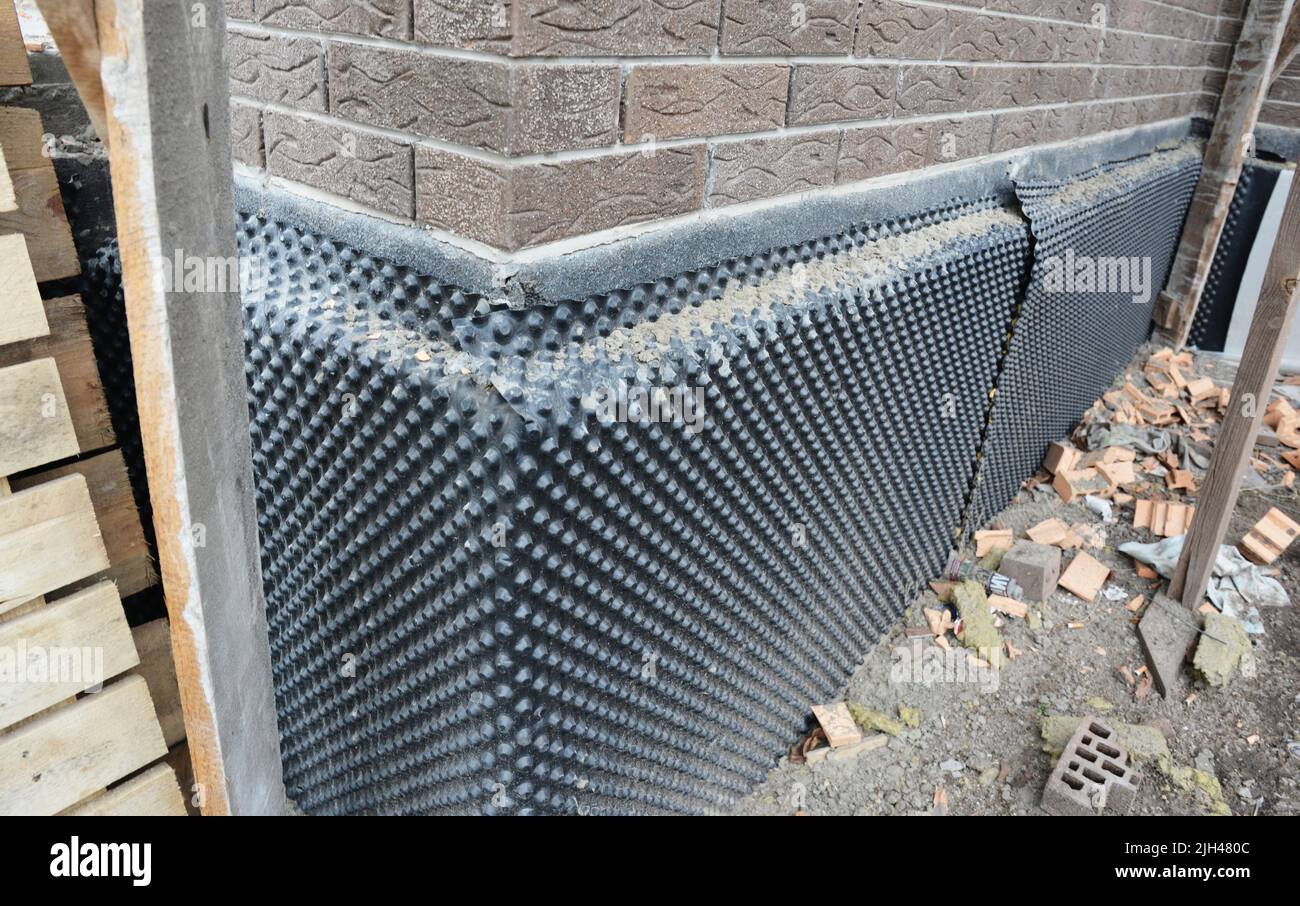 House foundation, basement waterproofing. Installation of a dimpled waterproofing membrane on