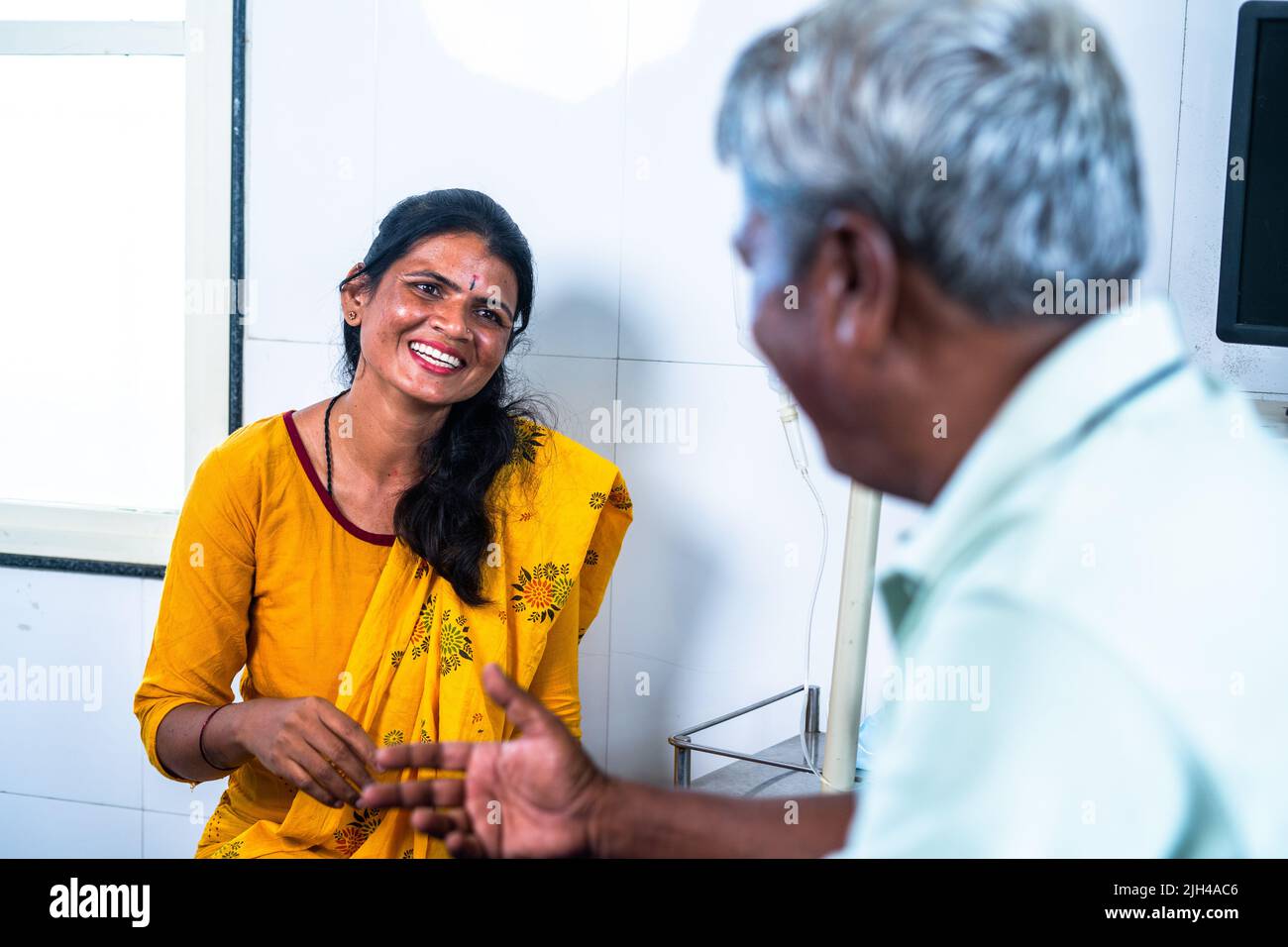 Happy smiling daughter with recovered father talking each other at hospital ward - concept of relationship, communication and treatment. Stock Photo
