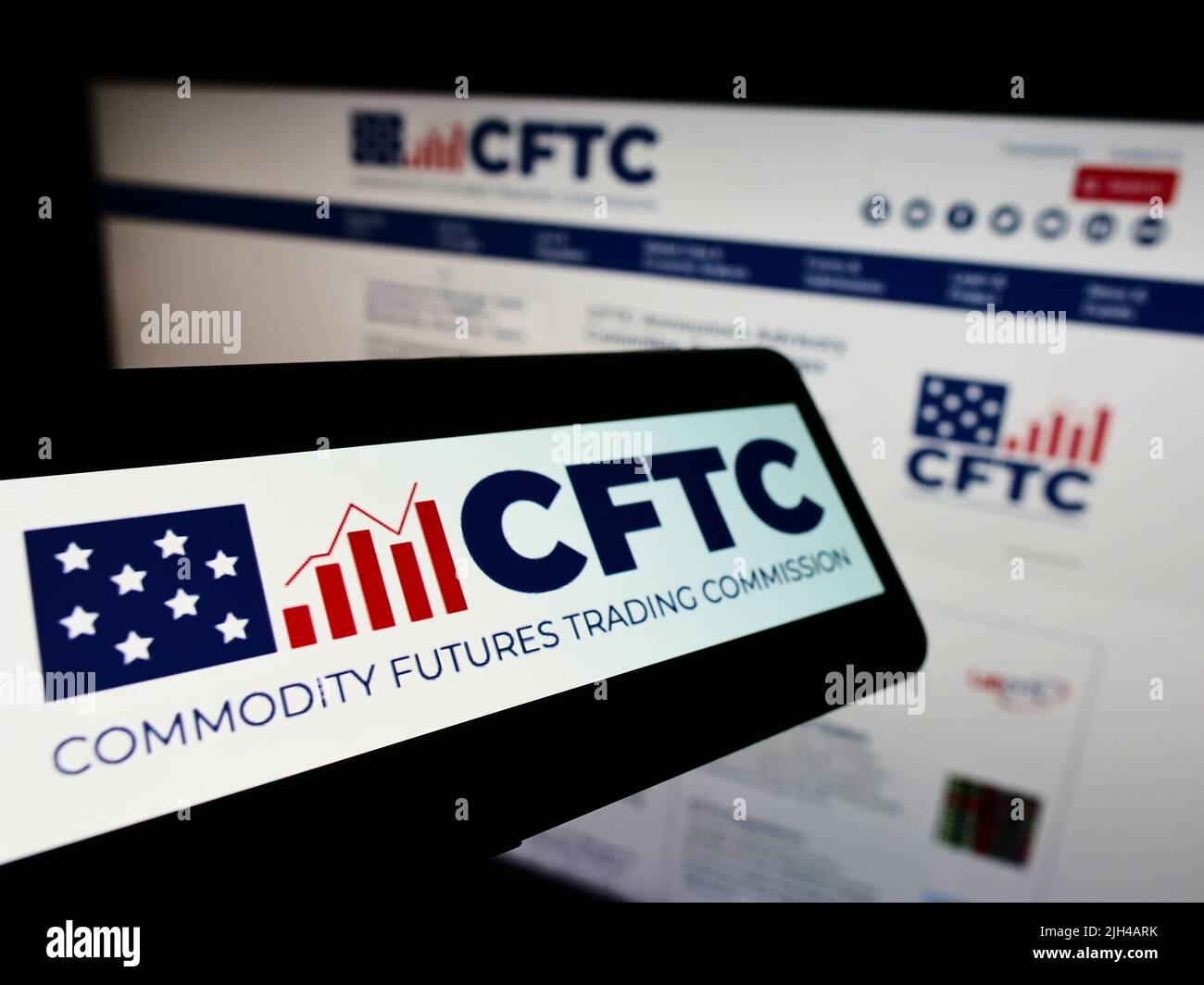 Smartphone with logo of American Commodity Futures Trading Commission (CFTC) on screen in front of website. Focus on center of phone display. Stock Photo