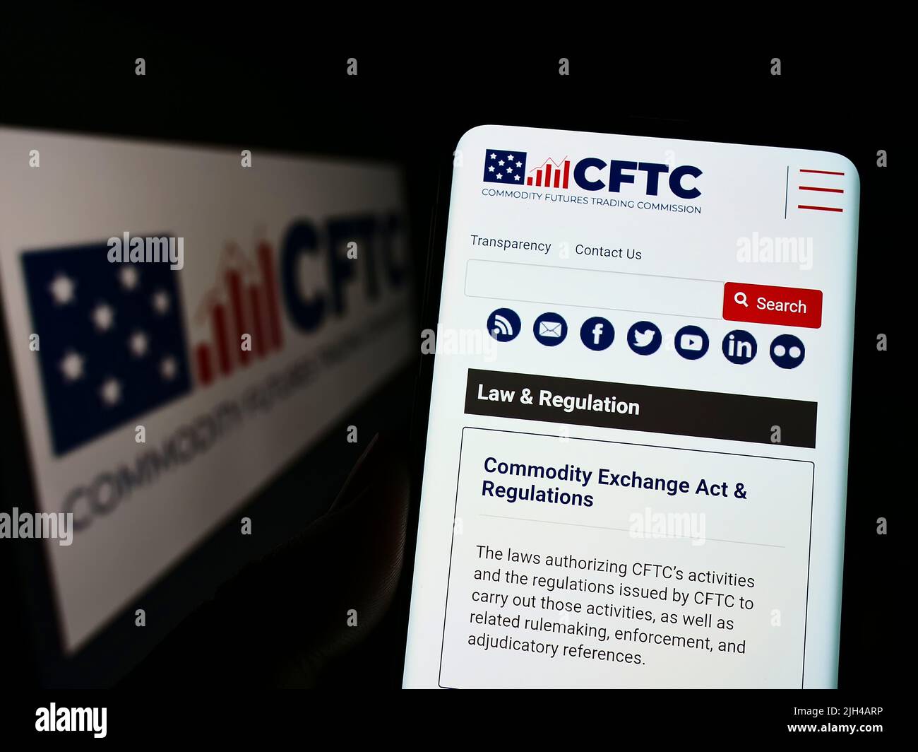 Person holding cellphone with webpage of US Commodity Futures Trading Commission (CFTC) on screen with logo. Focus on center of phone display. Stock Photo