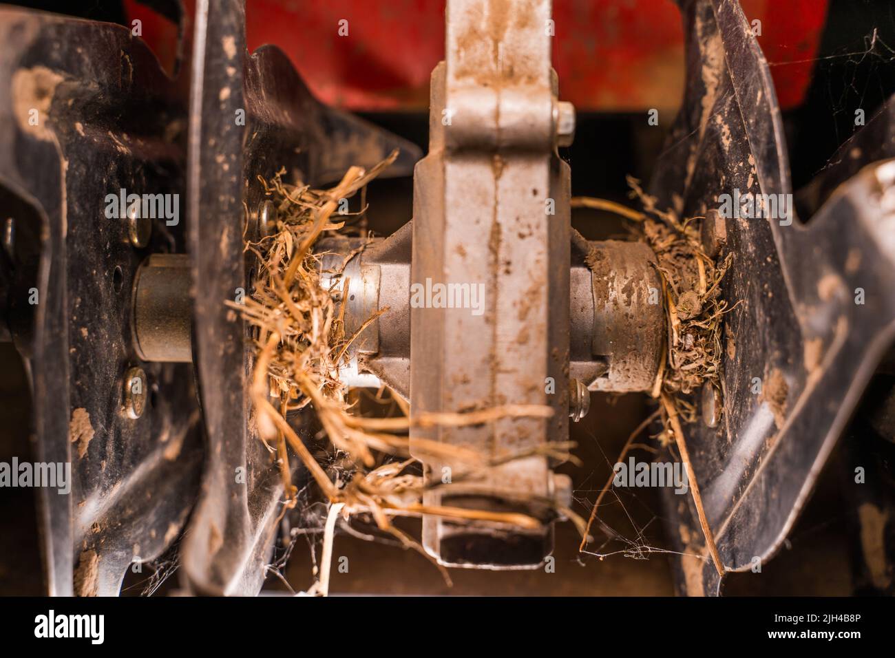 Rototiller of a walk-behind tractor with tangled dry grass close-up