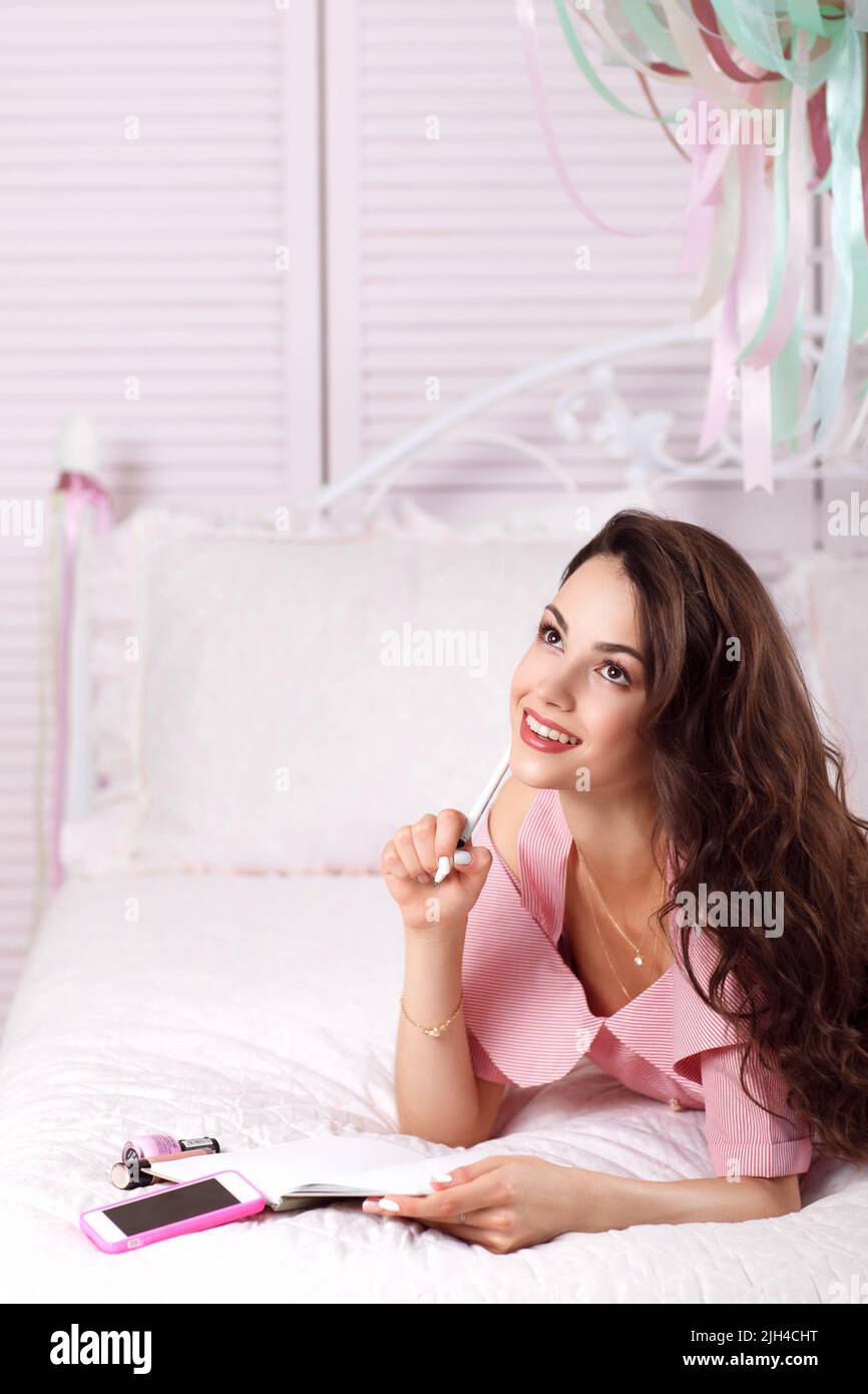 Dreaming woman lying in bed with copybook Stock Photo Alamy