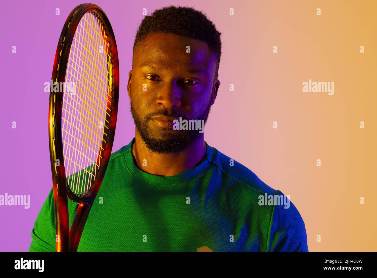 Image of african american male tennis player in violet and yellow neon lighting Stock Photo