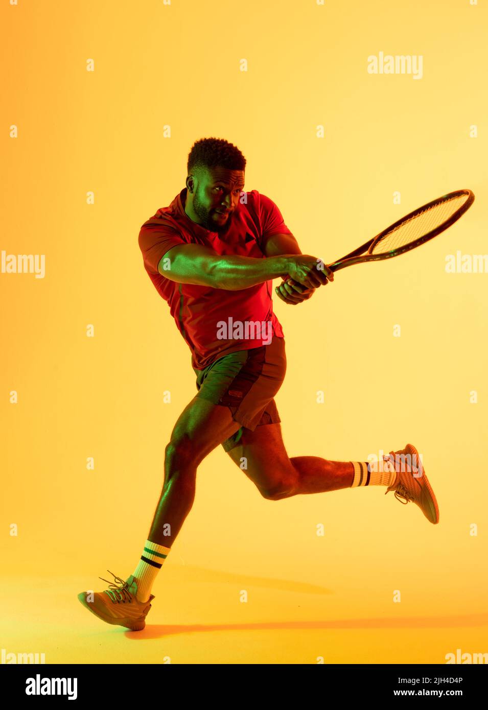 Vertical image of african american male tennis player hitting ball in