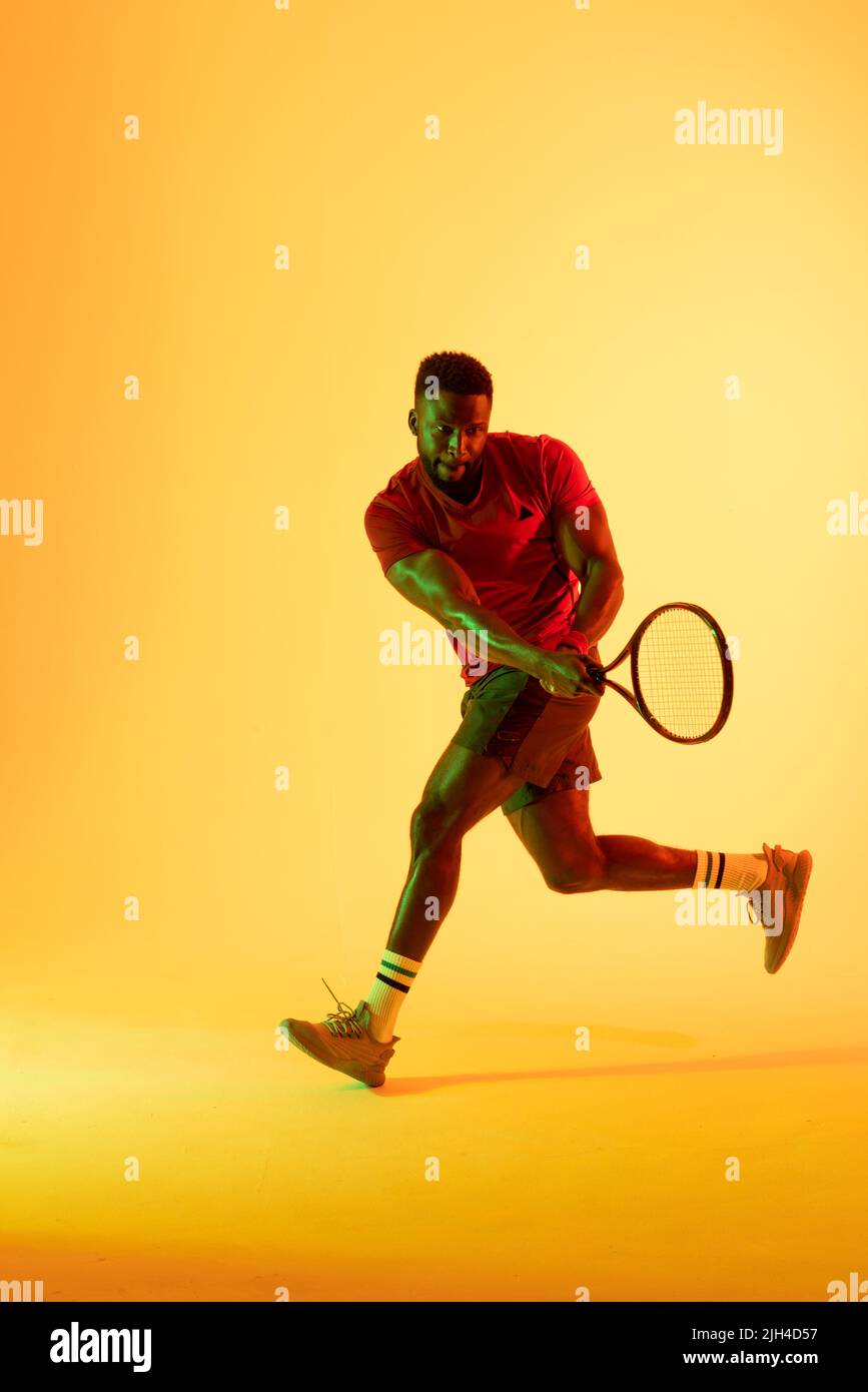 Vertical image of african american male tennis player hitting ball in