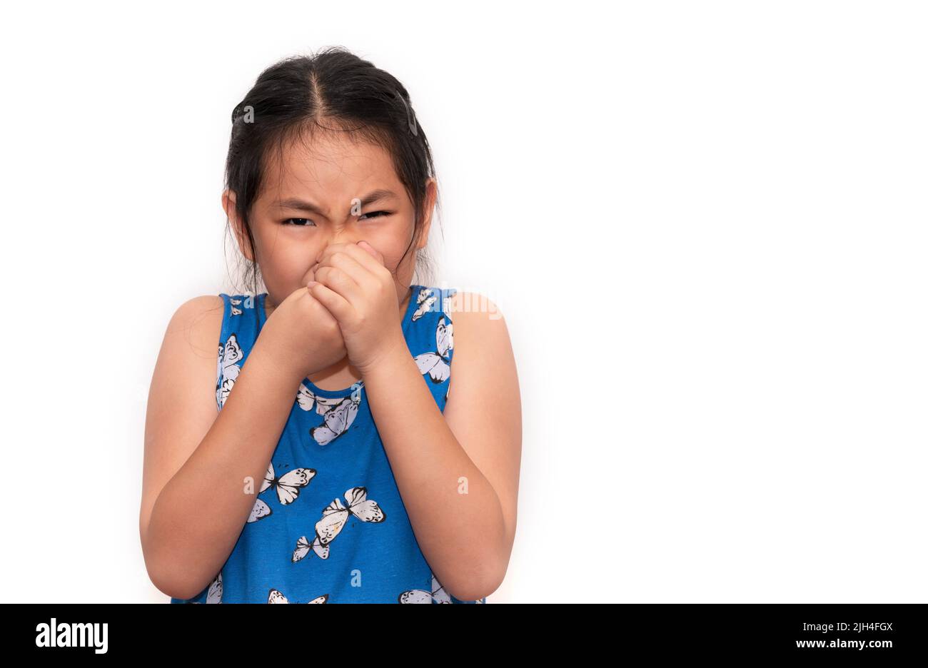 Cute Asian child girl is closing her nose with two hands, an unhappy child feeling bad from the smell, isolated portrait child girl on white backgroun Stock Photo