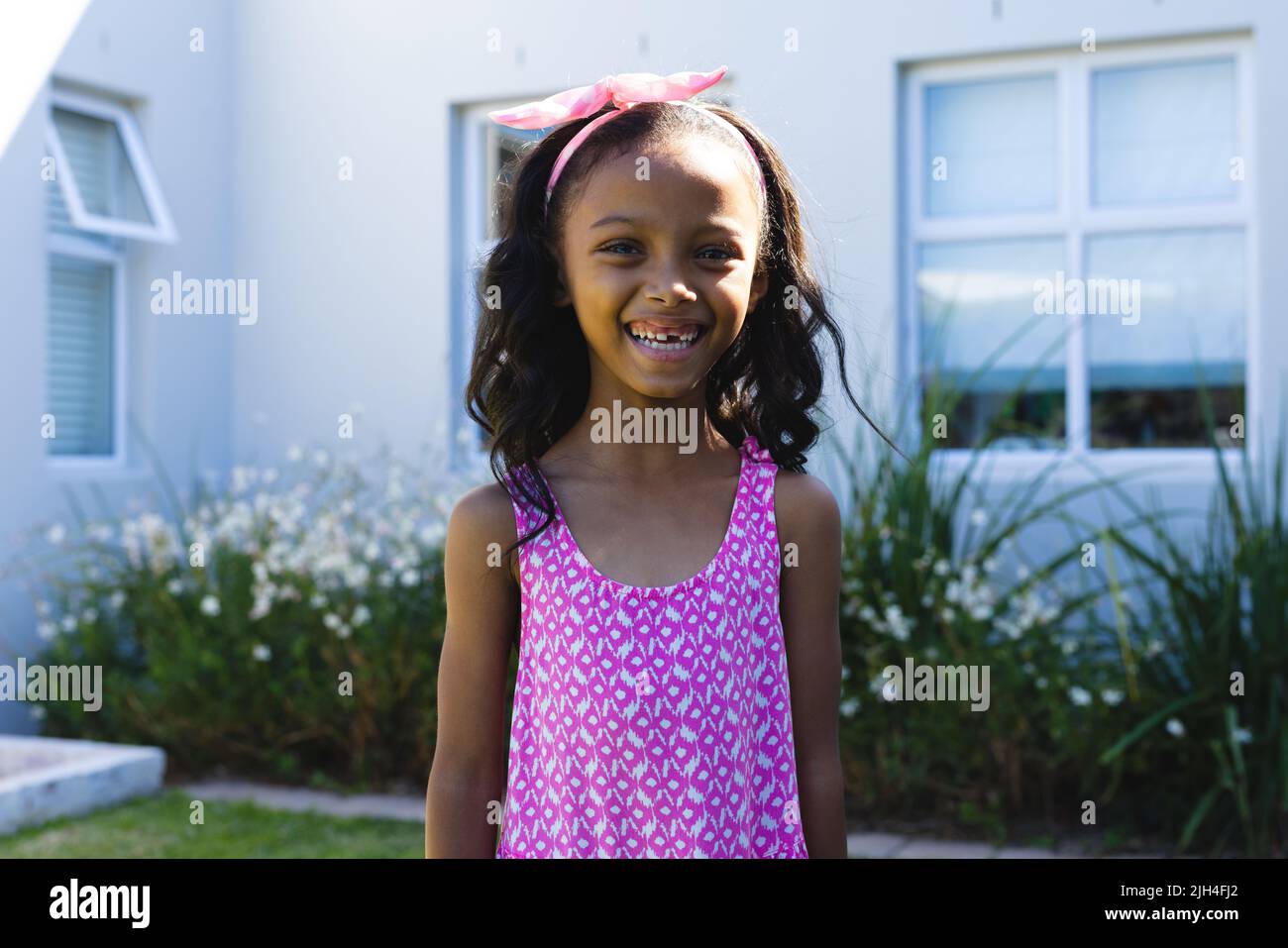 Portrait of biracial girl with missing tooth smiling while standing against house in yard Stock Photo