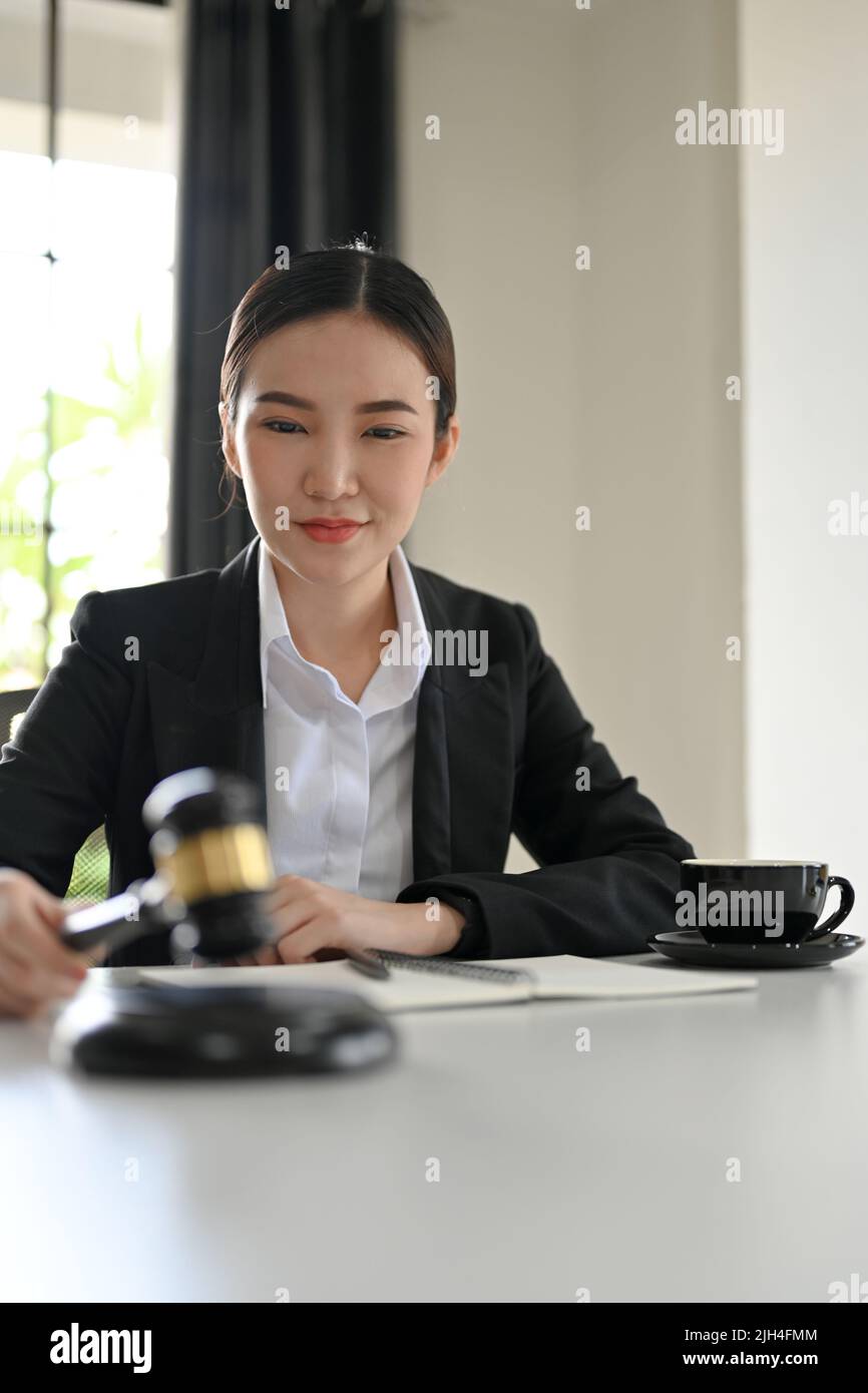 Portrait, Successful Asian female lawyer holding a judge hammer or judge gavel in the office courtroom. Lawyer, judge, business lawyer concept. Stock Photo