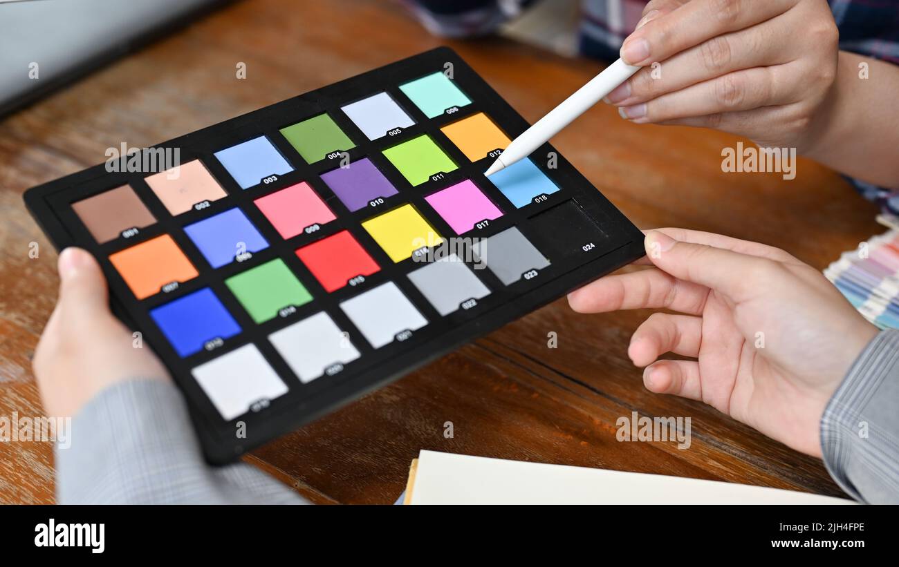 Close-up image, A female graphic designer or photo editor holding a colour checker chart. Stock Photo