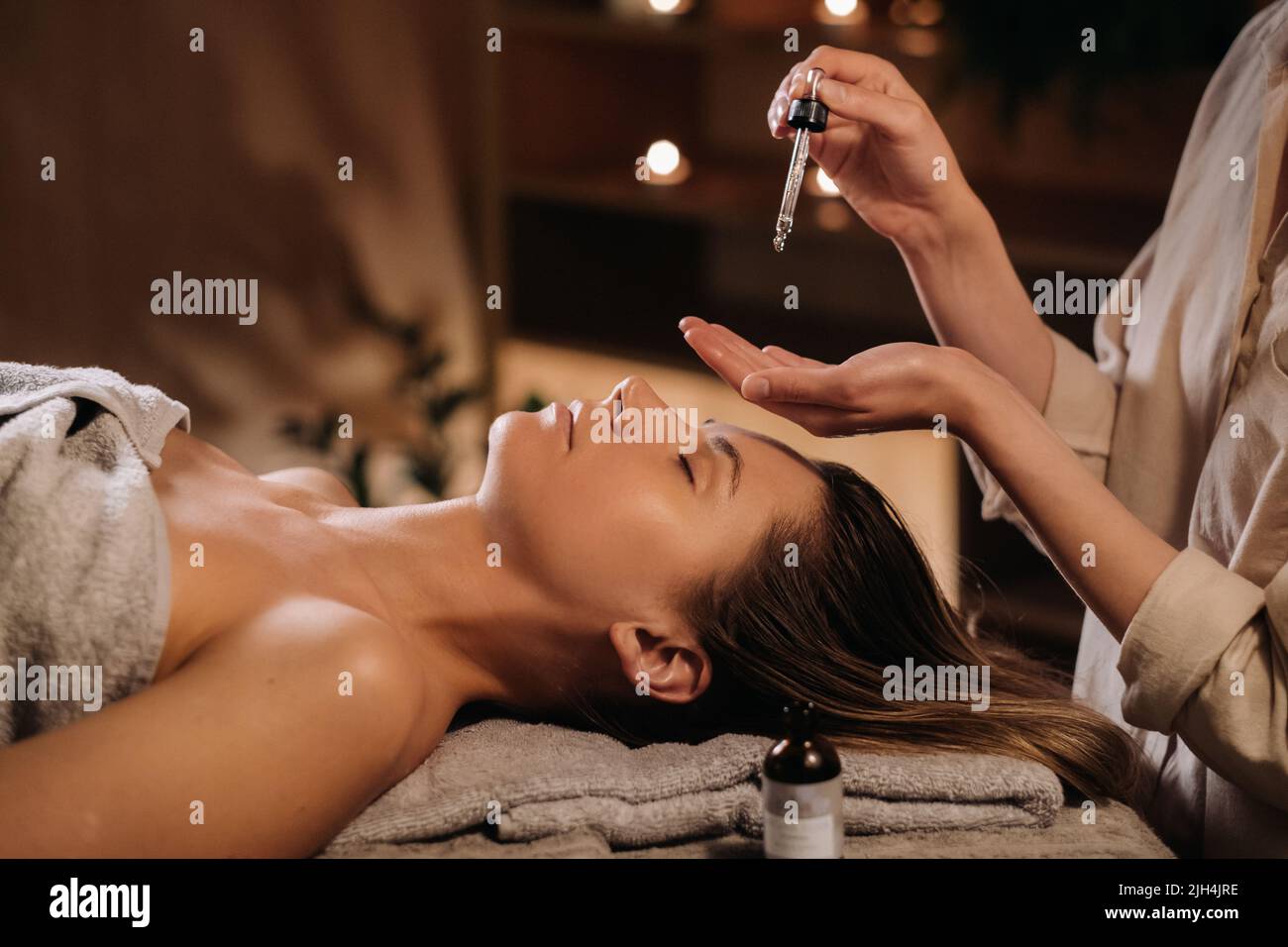 A female cosmetologist holds a pipette with essential oil before aromatherapy and massage to the patient. aromatherapy.Close-up. Stock Photo