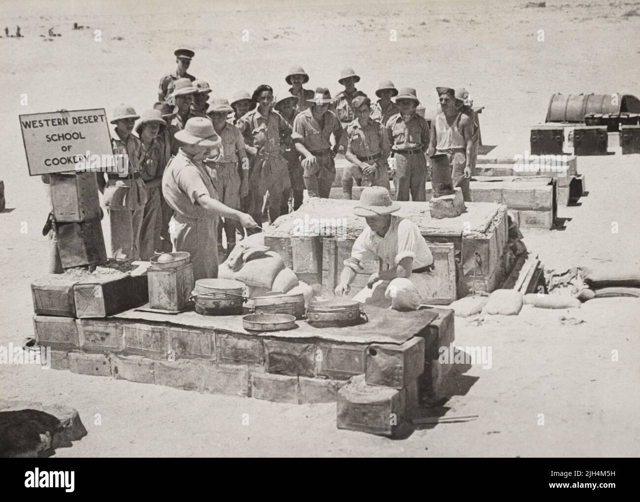 Unidentified British and Australian soldiers being trained preparing food on wood fired cooking stoves at the Western Desert Cookery School where army cooks were taught improvisation and how to make full use of field rations. The ovens are made out of petrol tins and oil drums. Stock Photo