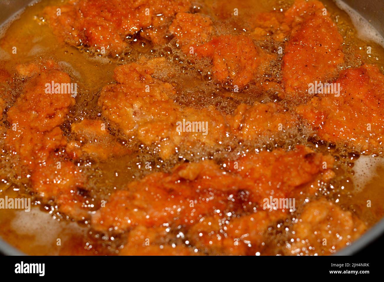 Frying chicken strips in deep oil background, selective focus of