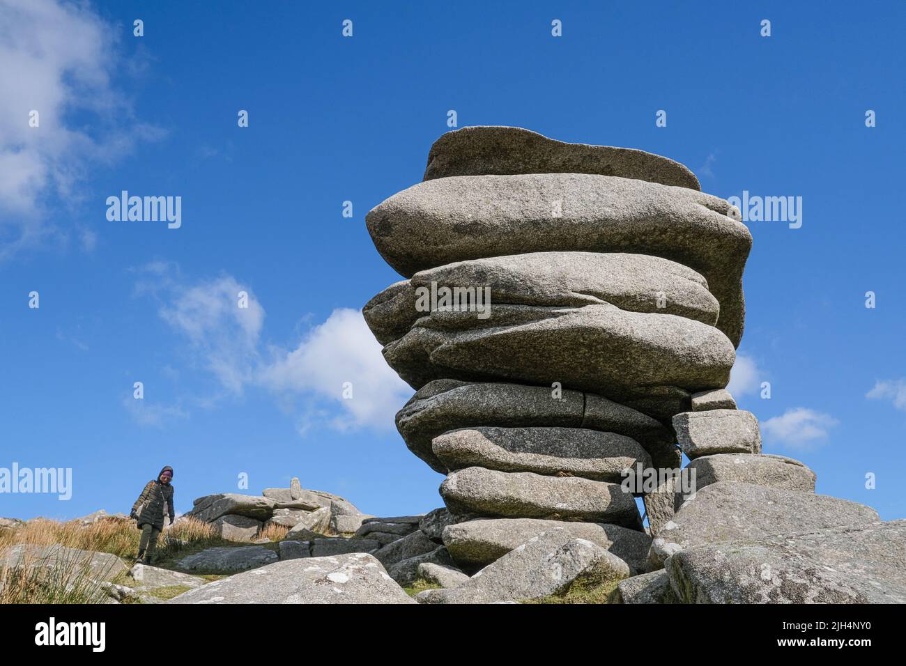 A walker next to the towering granite rock stack The Cheesewring left by glacial action on Stowes Hill on Bodmin Moor in Cornwall. Stock Photo