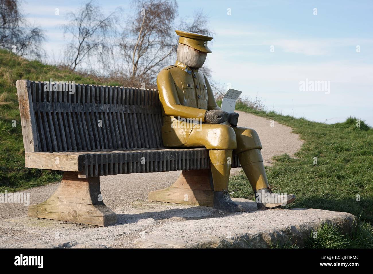 Sculpture of WW1 soldier reading letter seated on bench along coastal path, Flint, north Wales Stock Photo