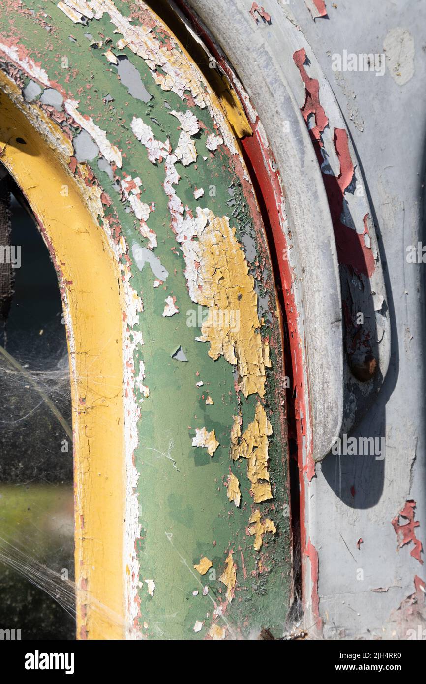 Weathered green, grey, red and yellow peeling paint on an old metal truck cab Stock Photo