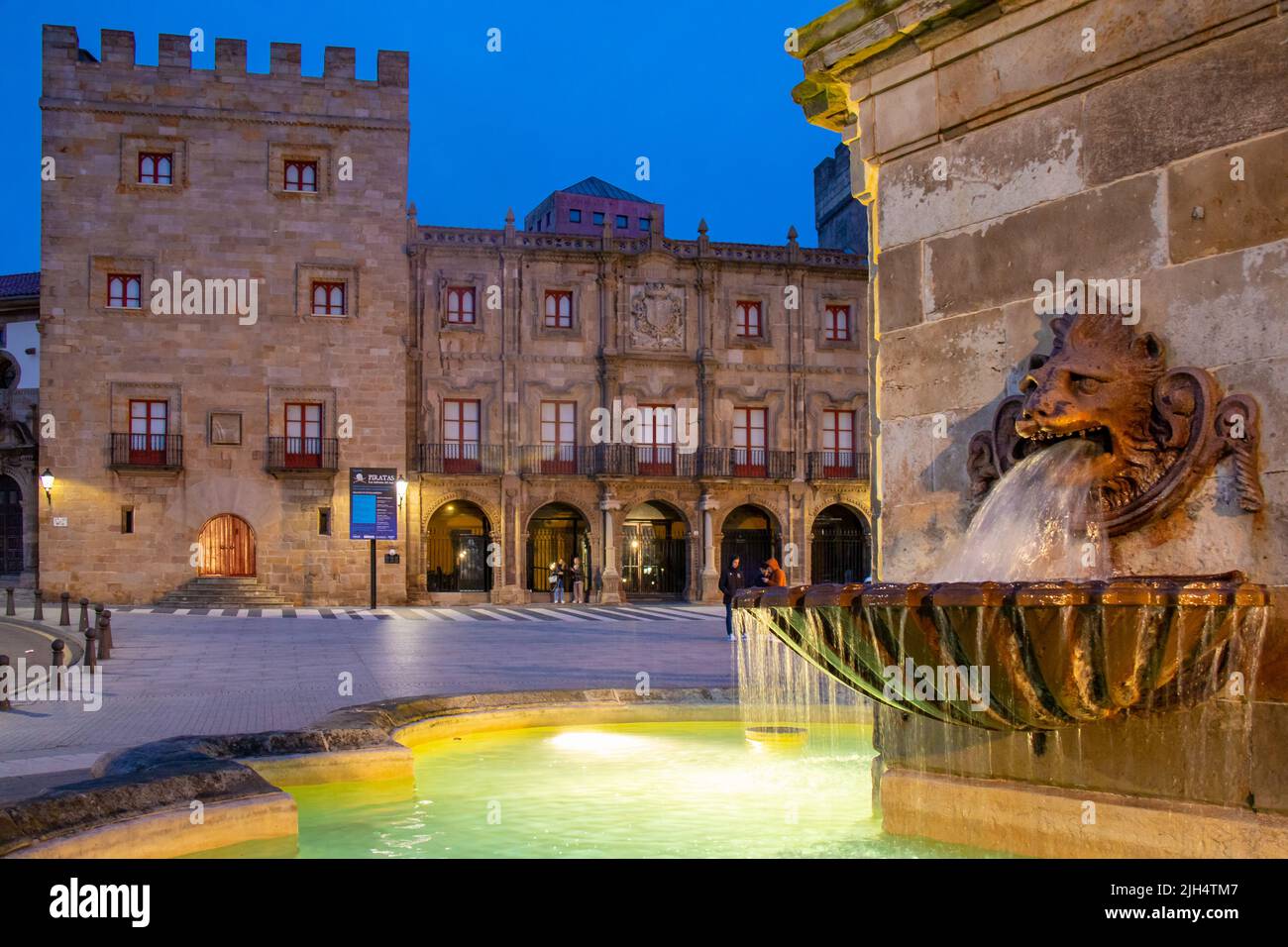 Por la noche la fuente del león y al fondo el Palacio de Revillagigedo, Gijón, España Stock Photo
