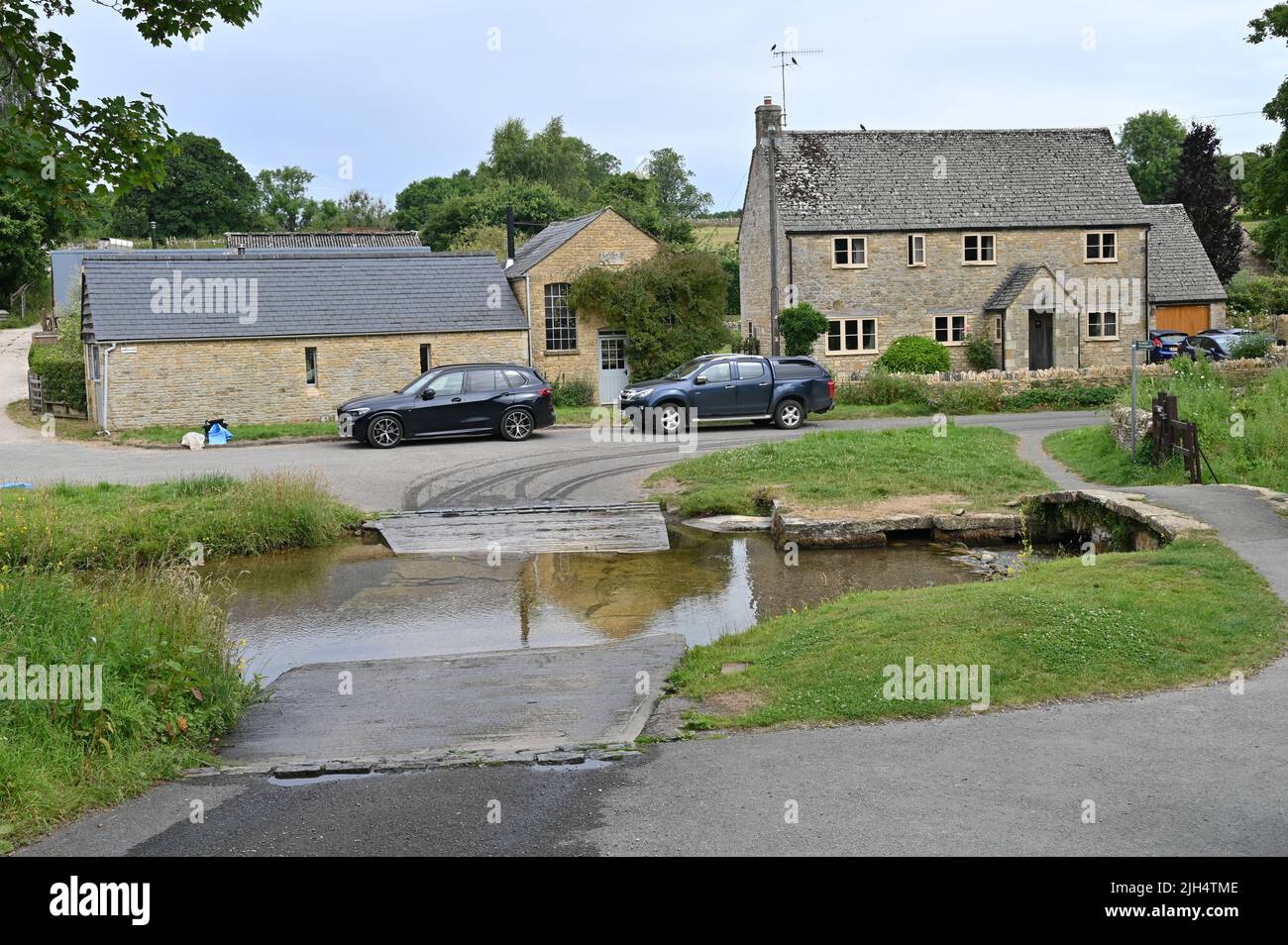 The River Eye is forded in the pretty Cotswolds village of Upper Slaughter, Gloucestershire. Passage can be hazardous after a spell of heavy rainfall Stock Photo