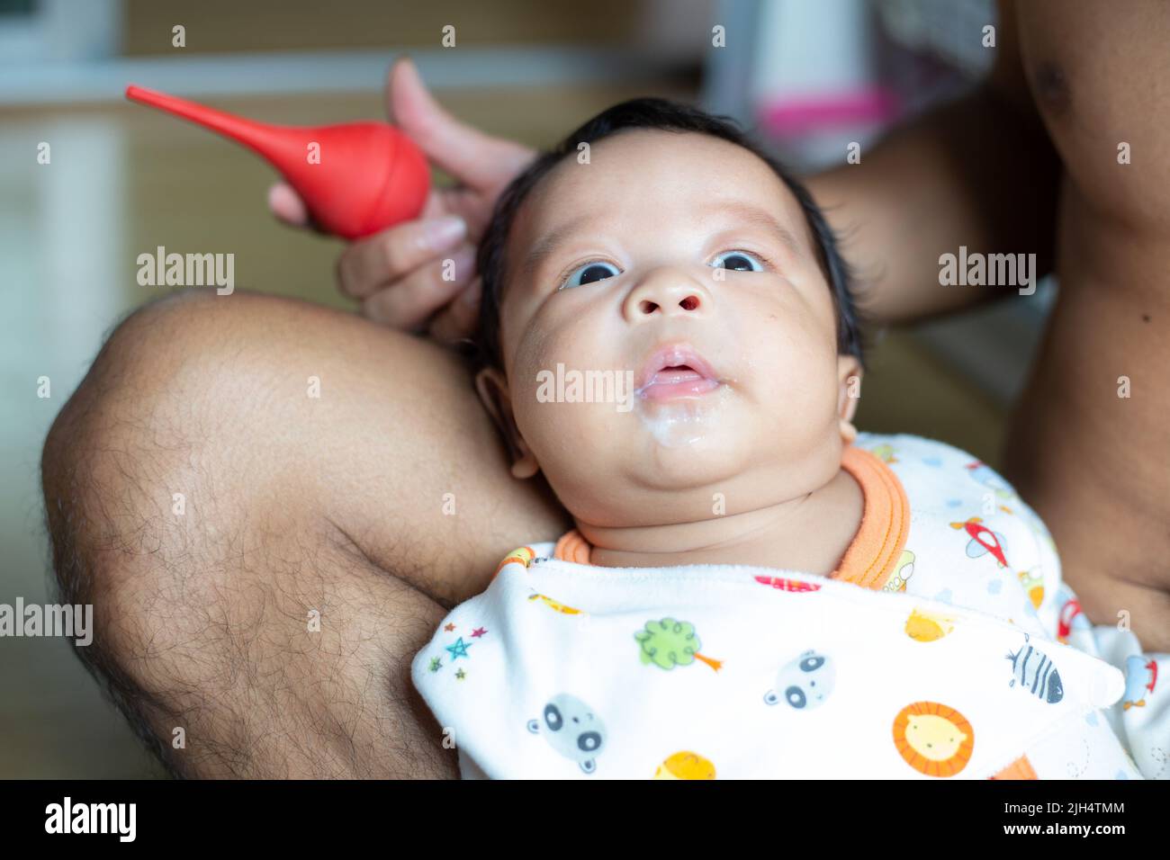 Dad hand use baby nasal aspirator mucus nose suction sucking the saliva