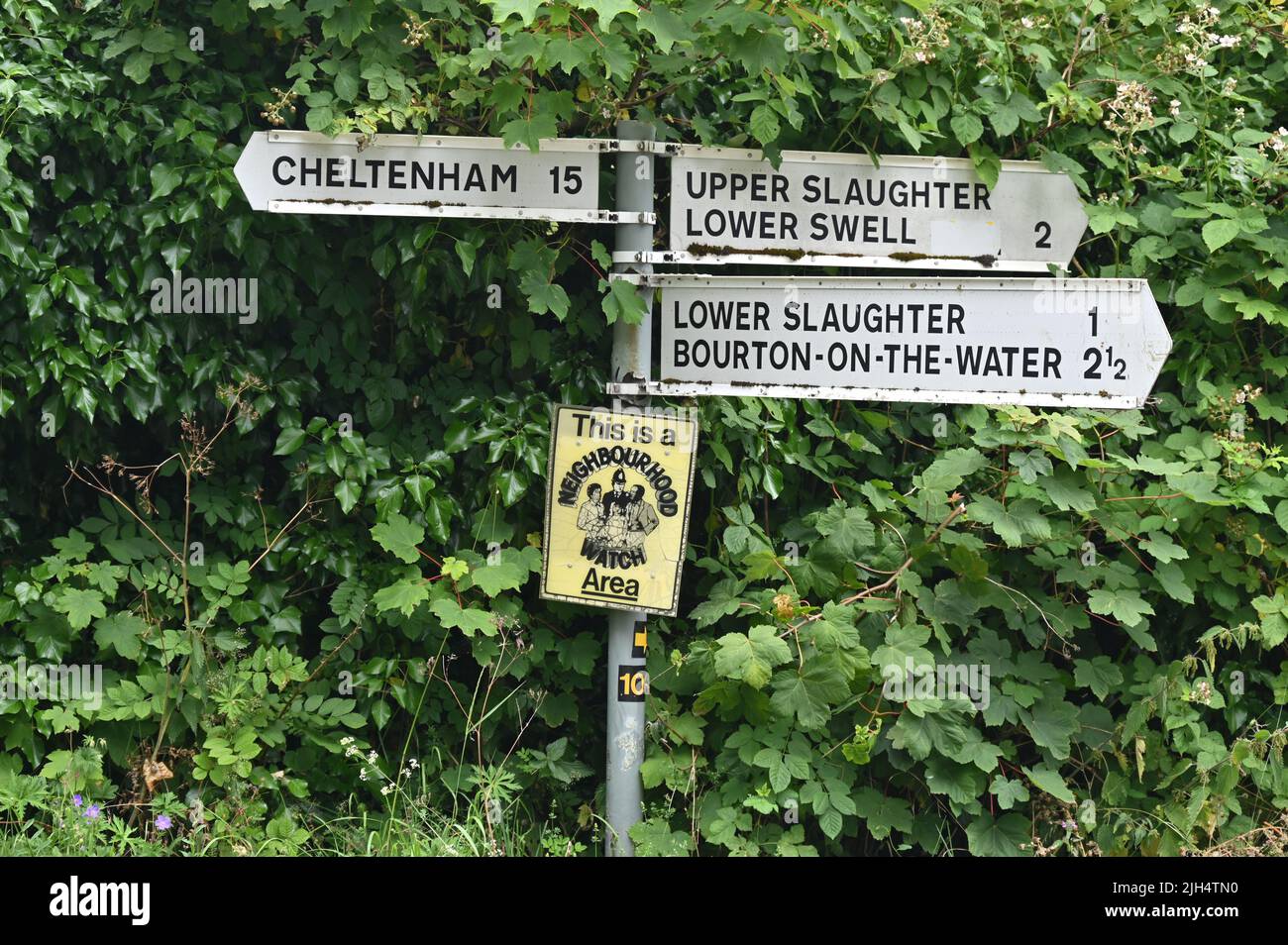 Direction signpost near the Gloucestershire village of Upper Slaughter with a Neighbourhood Watch notice attached to it. Stock Photo