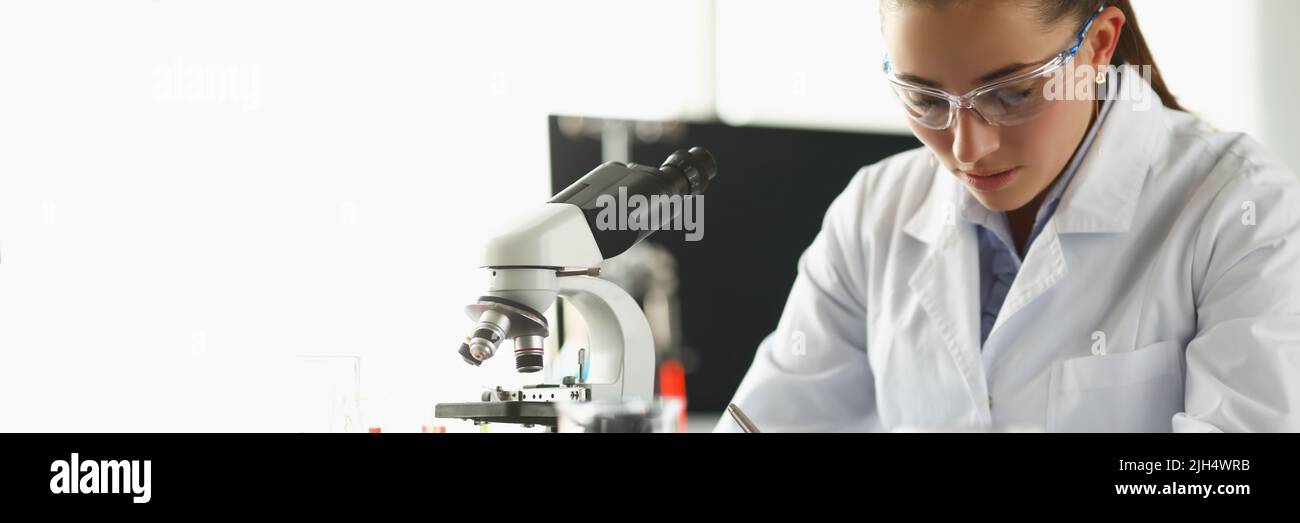 Concentrated chemist worker write down thoughts on investigation project in lab Stock Photo