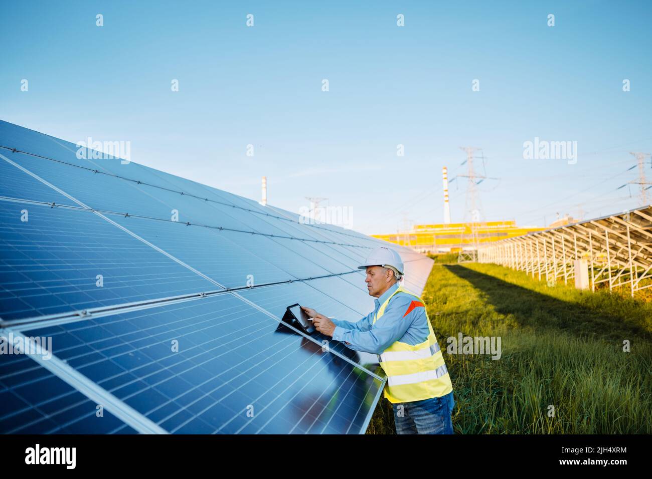 Tablet Using Solar Panel Mature industrial worker using tablet while monitoring rows of ...