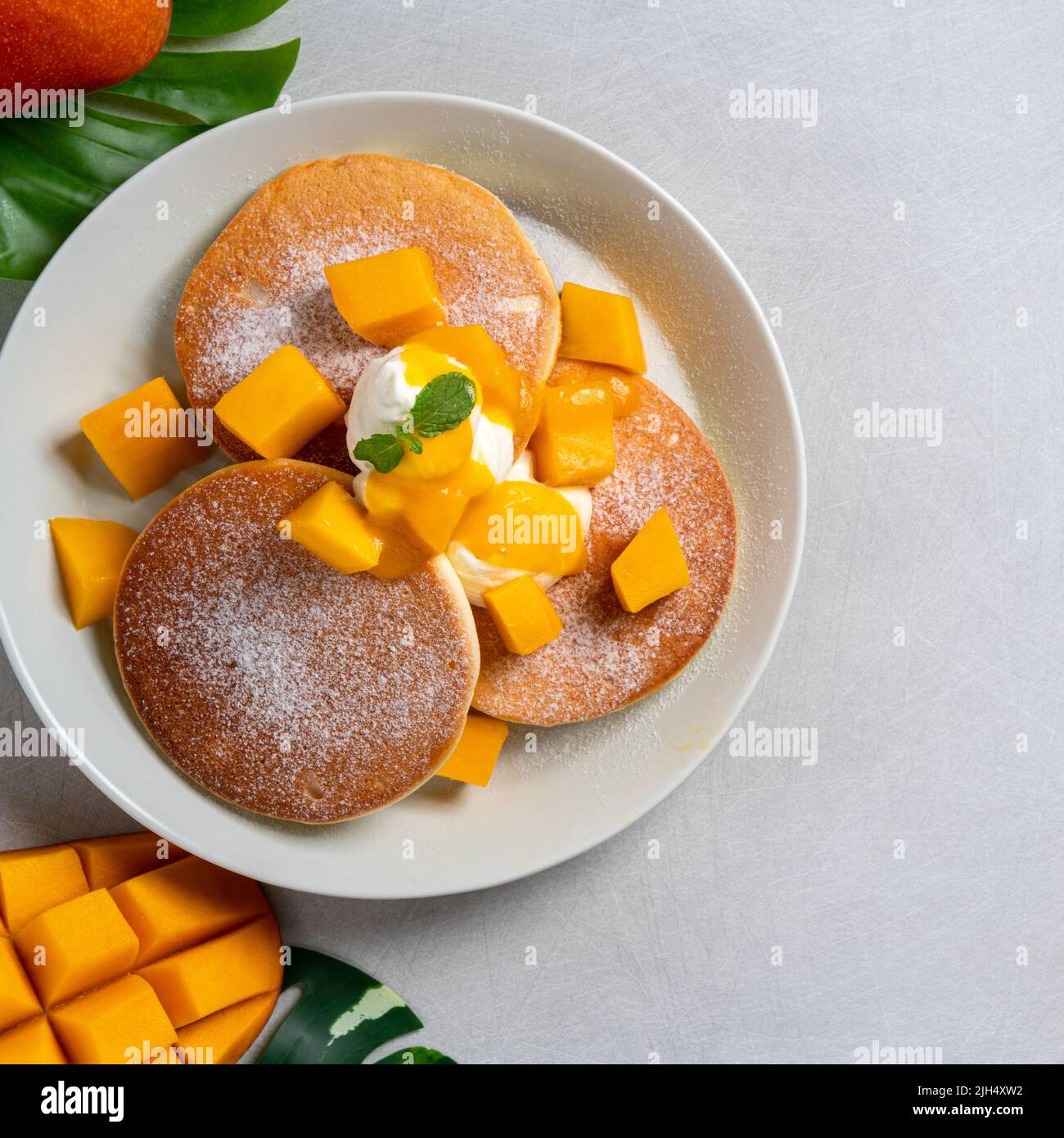Delicious Japanese souffle pancake with dice mango fruit pulps and jam on white table background. Stock Photo
