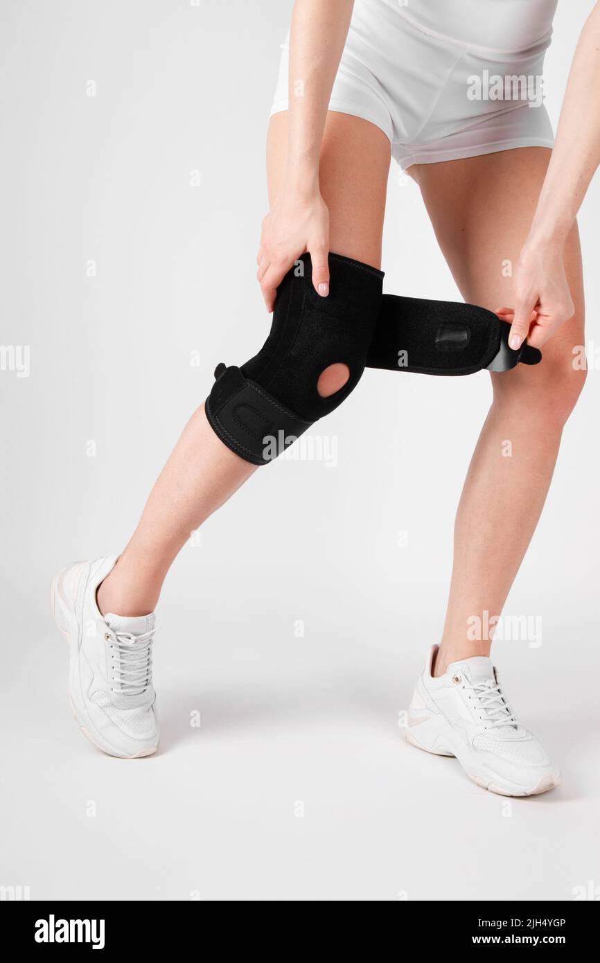 Knee Support Brace on leg isolated on white background. Elastic orthopedic orthosis. Anatomic braces for knee fixation, injuries and pain. Protective Stock Photo