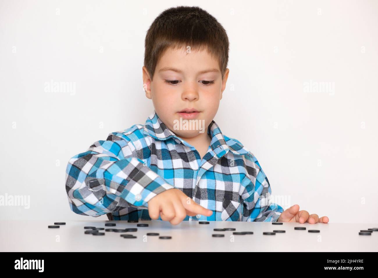 A 4-year-old boy is learning to count, teaching black numeracy chips for preschoolers Stock Photo