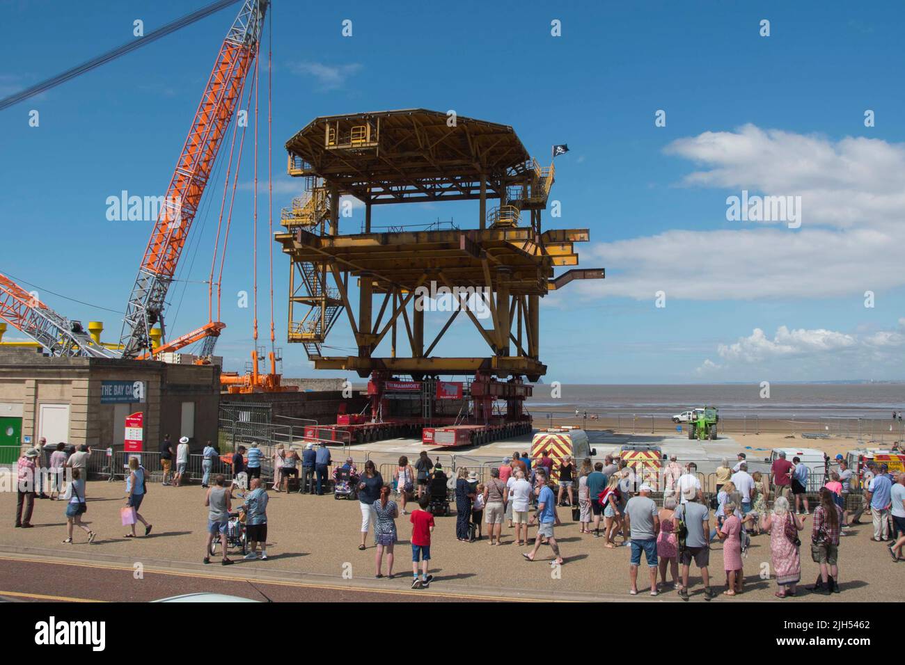 Weston-super-Mare, Somerset, UK.  15th July 2022.  The 25 meter tall North Sea platform, turned art installation called the See Monster being readied on the beach at Weston-Super-Mare in Somerset for it to be lifted on to its already installed legs next to the Tropicana.  A large crowd is building on the seafront awaiting the lift which is expected to happen today.  Picture Credit: Graham Hunt/Alamy Live News Stock Photo