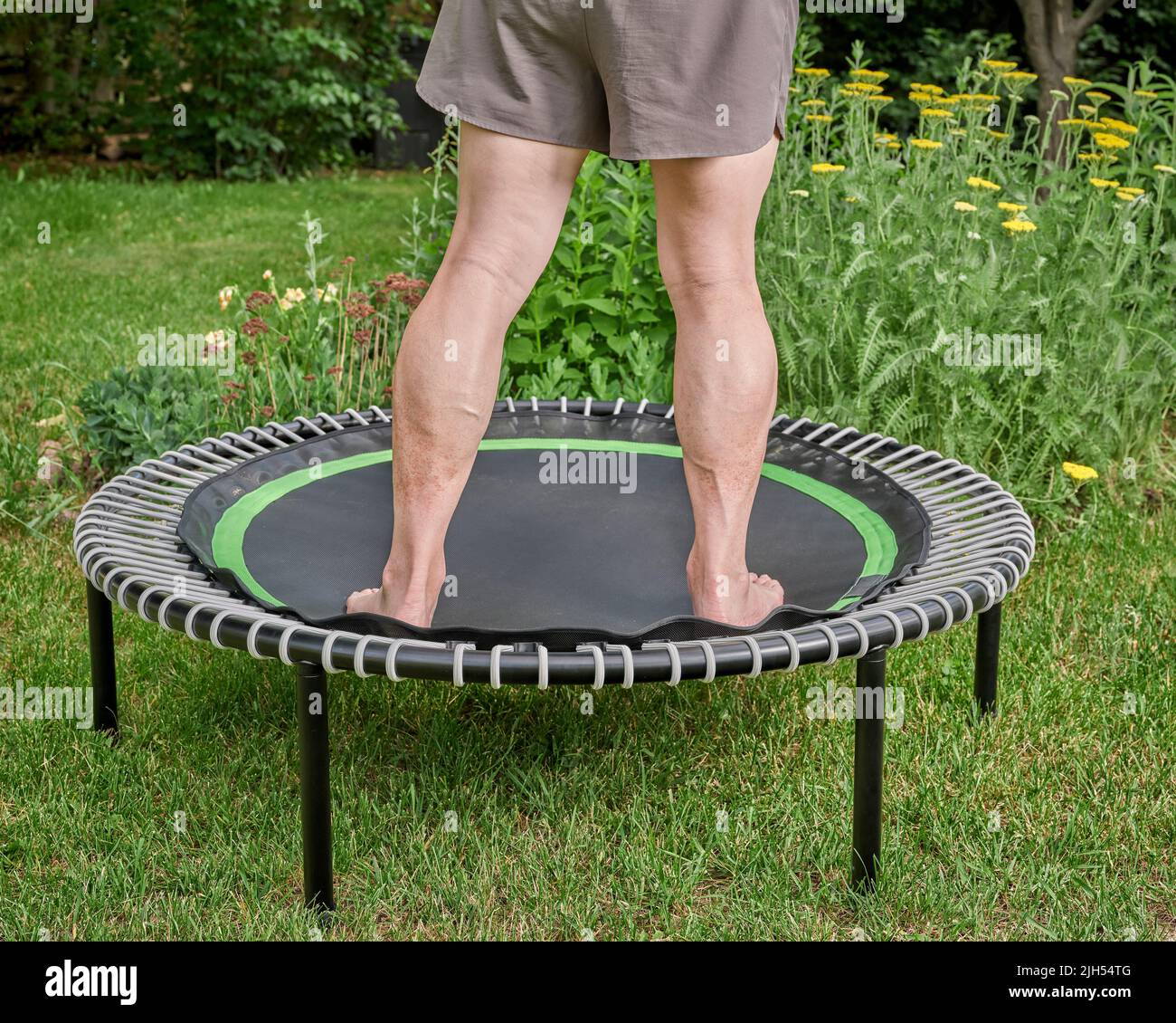 rebounding concept feet and legs of a muscular man jumping on a mini