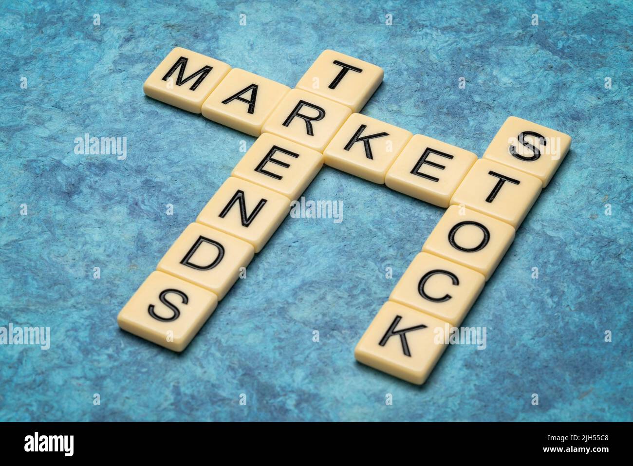 stock market trends crossword in ivory letter tiles against textured handmade paper, business