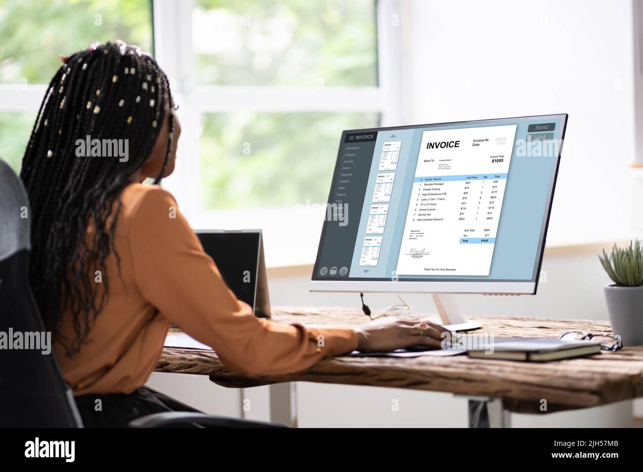 African American Lady Using Computer For Online Invoice Calculation Stock Photo