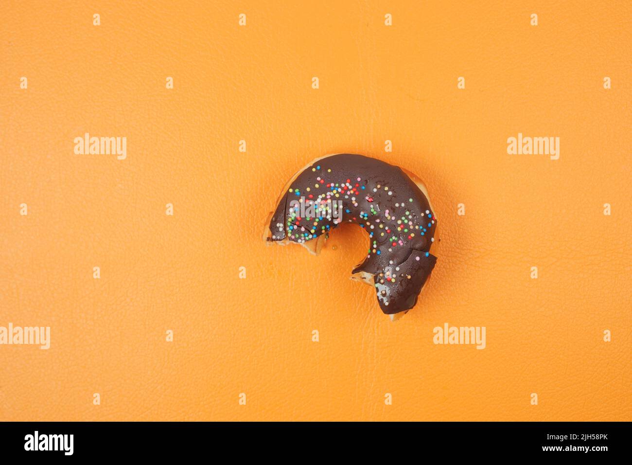 half eaten donuts and coffee mug on orange background  Stock Photo
