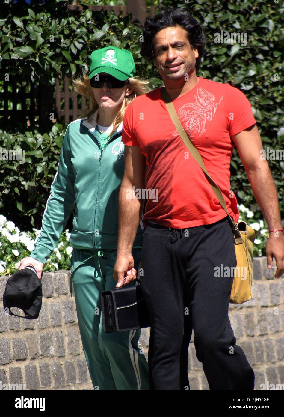 **EXCLUSIVE**PICTURES**TRUE**GREEN!** MADONNA STROLLS OUT FOR LUNCH WITH HER FITNESS/GYROTRONIC GURU JAMES D'SILVA NEAR HER LONDON MANSION TODAY SPORTING A SKULL AND CROSSBONE MOTIF BASEBALL CAP WITH MATCHING TRACKSUIT. MADONNA WAS CLUTCHING A BOTTLE CONTAINING A MYSTERY DRINK. Stock Photo