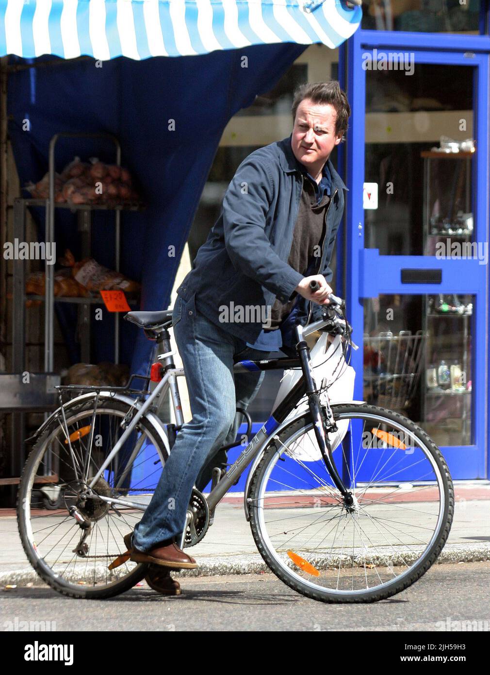 David Cameron is clearly a man of his word as he uses his bike to do the family grocery shopping at his local shops. Clearly not for Mr. Cameron is the 'celebrity style' supermarket style deliveries as the 'modern man' loads his bike in a true left/right balancing act as he swung to right infront of a juuggernaut! Next time maybe a set of cycling safety gear might be appropriate. Picture by Tony Henshaw Stock Photo