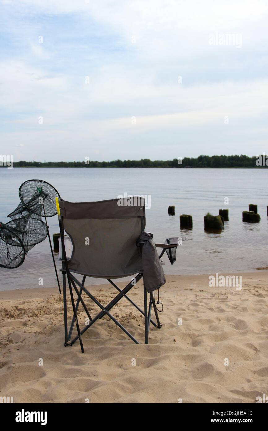 Folding chair and fish tank stand at the beach. Fishing singly. Stock Photo