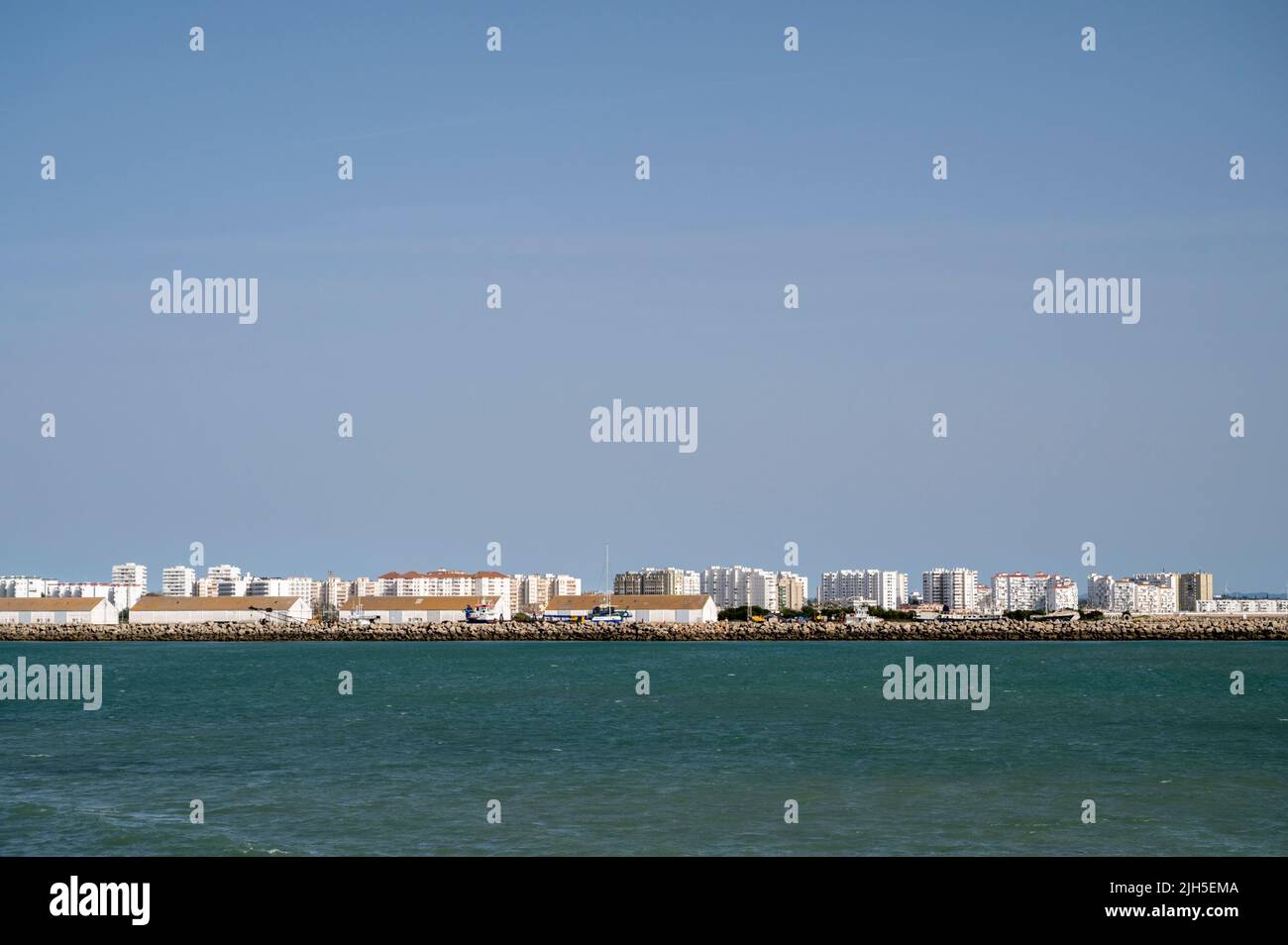 A view of a beach and buildings in the distance looking towards Cadiz from Puerto Santa Maria Spain Stock Photo