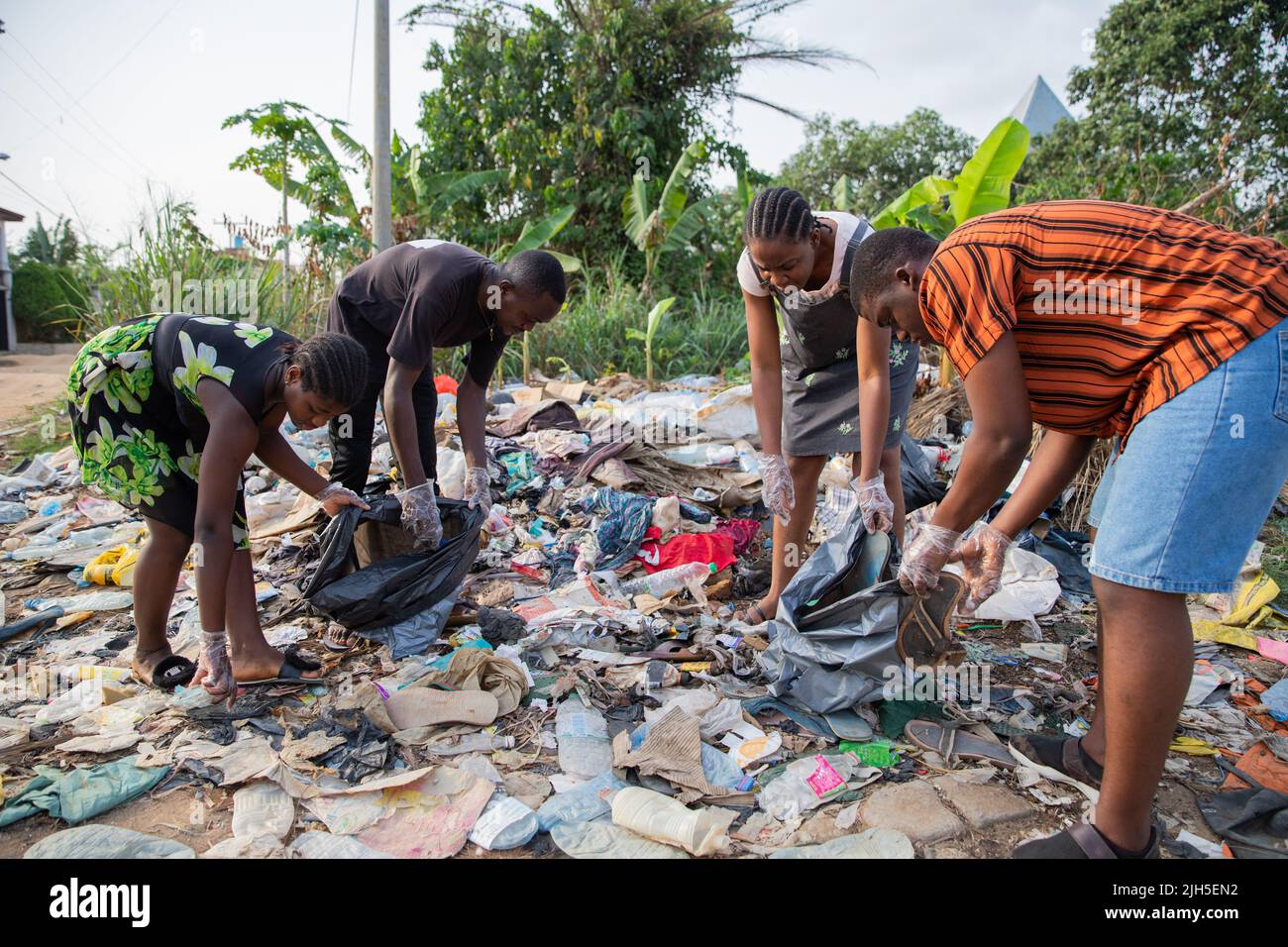 Four young adults collect garbage in an illegal openair landfill in