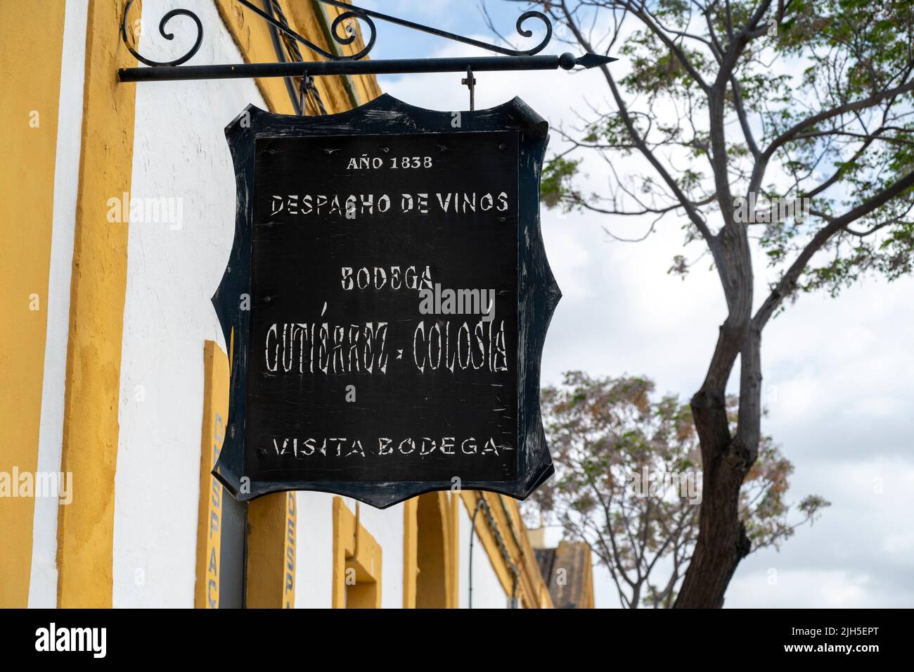 A sign on an old sherry warehouse and bodega painted in white with yellow skirting, by Gutierrrez Colosia in Puerto de Santa Maria Spain Stock Photo