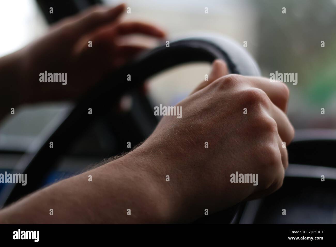 Defocus male hand holding steering wheel. A man's hand handle steering