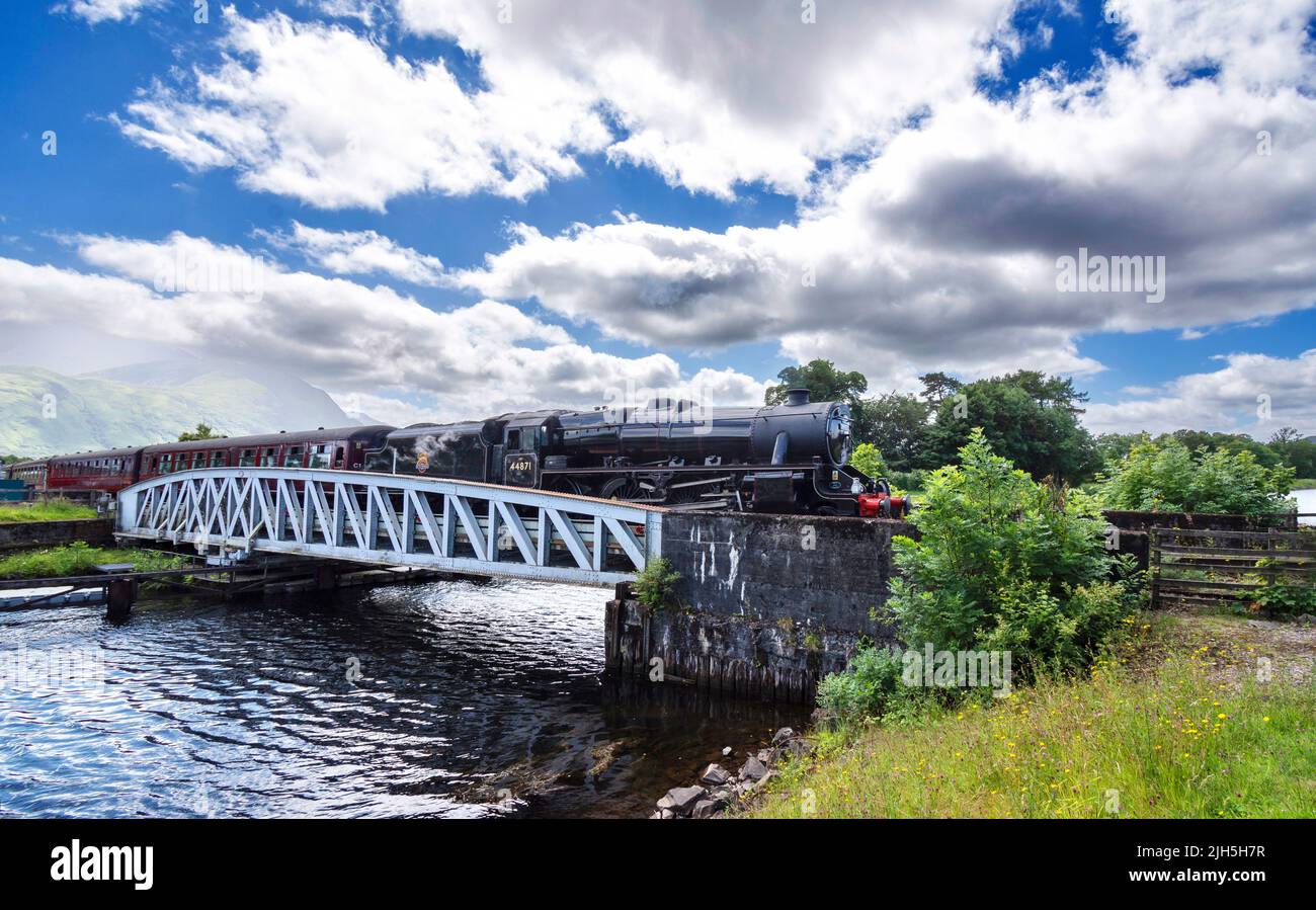 FORT WILLIAM SCOTLAND JACOBITE STEAM TRAIN CROSSING BANAVIE METAL SWING BRIDGE WITH BEN NEVIS IN THE BACKGROUND Stock Photo